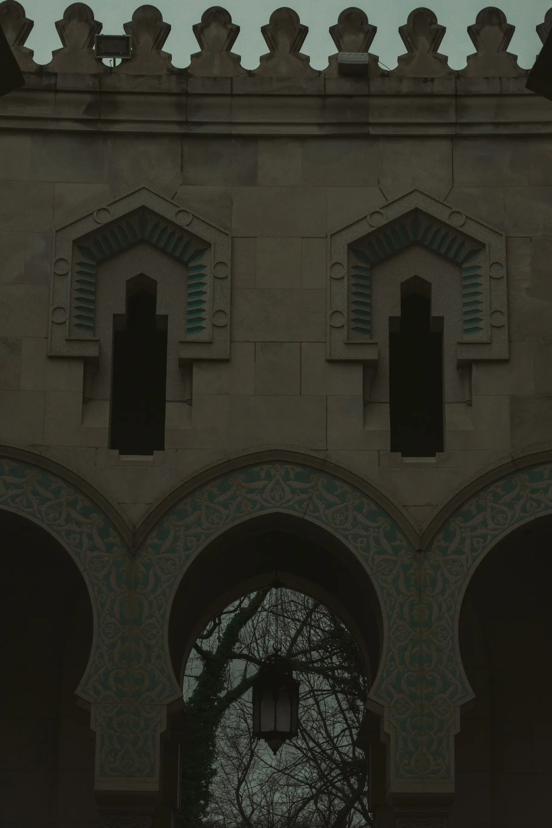 Ornate Islamic-style stone archway and windows against a dusk sky