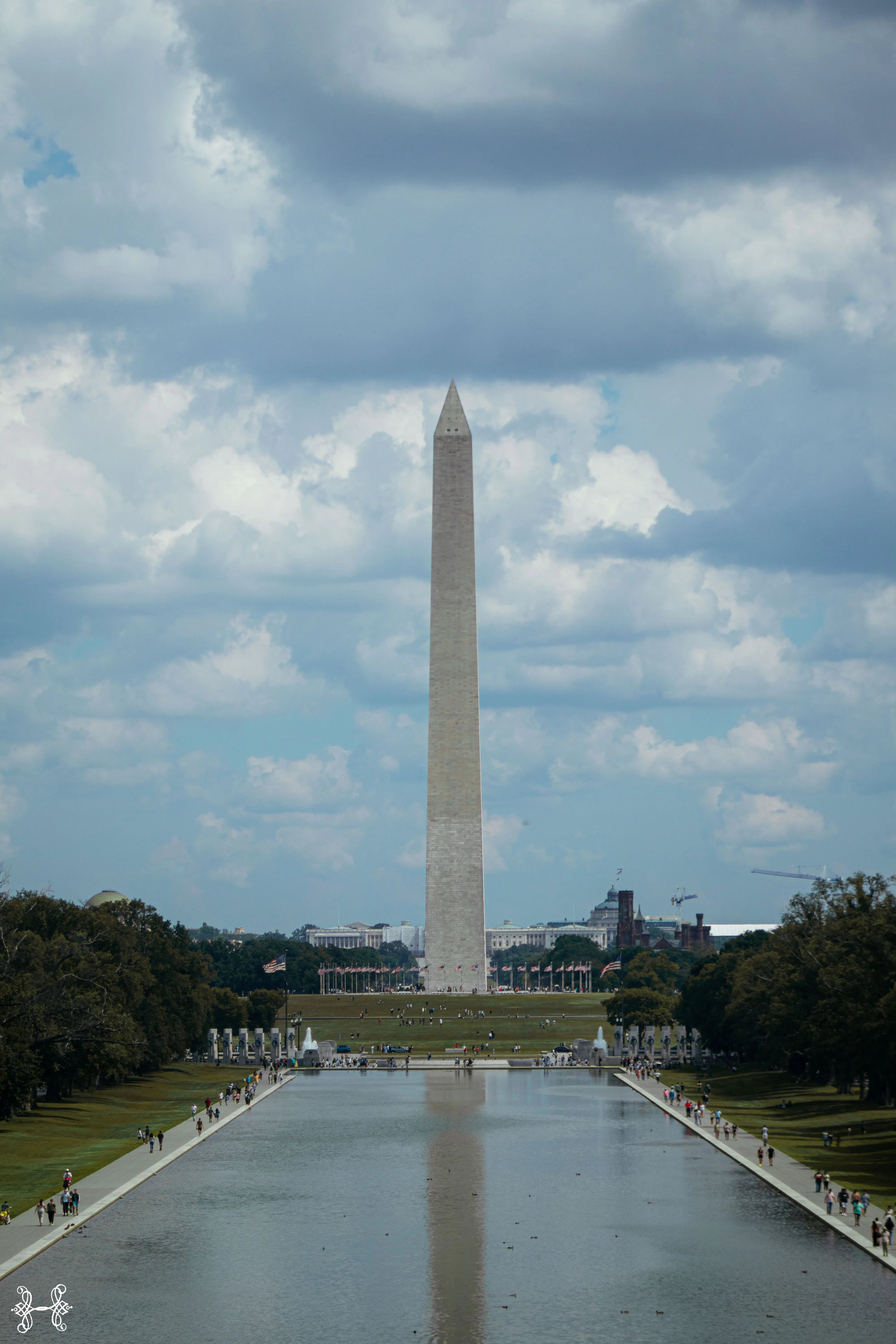 The Washington Monument reflected in the Reflecting Pool under a cloudy sky